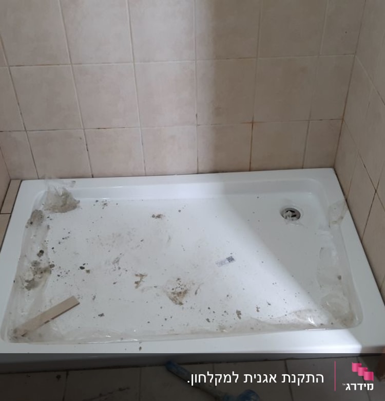 מגש מקלחת מלוכלך עם כלי עבודה על הרצפה